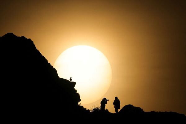 Пара фотографируется во время заката на вершине &quot;Порт д&#x27;Аваль&quot;, знаменитой арки скал Этрета на западе Франции - Sputnik Грузия