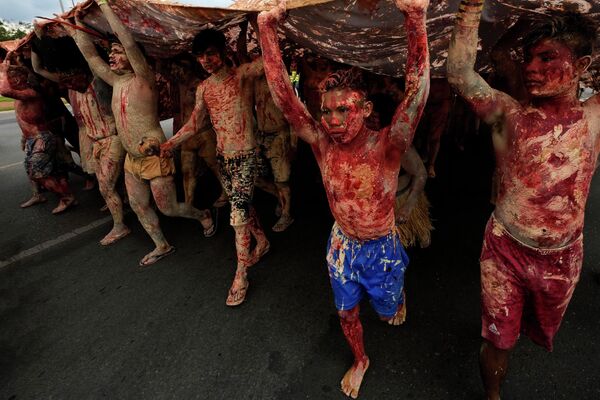 Коренные жители Бразилии, раскрашенные красными чернилами, изображающими пролитую кровь коренных народов, с глиной, символизирующей золото, маршируют во время акции протеста против увеличения добычи полезных ископаемых - Sputnik Грузия