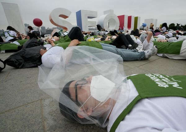 Активист с полиэтиленовым пакетом на голове лежит на земле во время перформанса, посвященного Дню Земли против изменения климата в Сеуле - Sputnik Грузия