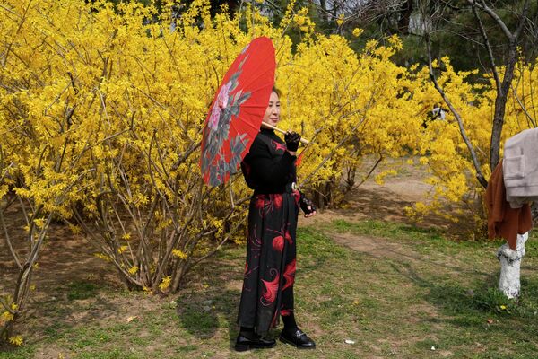 Женщина позирует рядом с цветами в пекинском парке - Sputnik Грузия