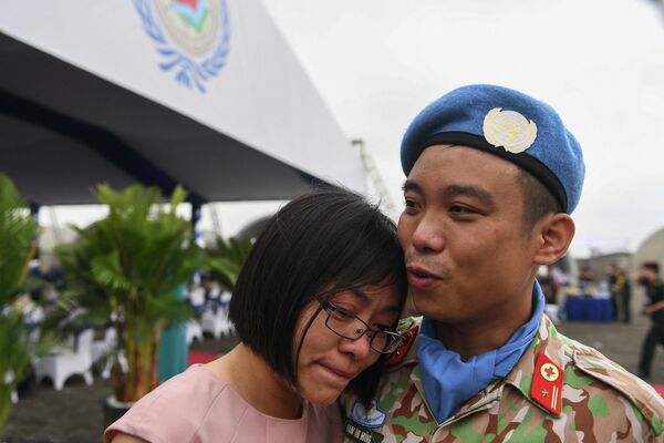 Военнослужащий вьетнамских сил, принимающий участие в миротворческой миссии Организации Объединенных Наций в Южном Судане, утешает свою жену перед отъездом в Ханой  - Sputnik Грузия