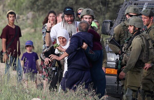 Израильские солдаты наблюдают, как поселенцы из Элон-Море дерутся с палестинскими фермерами, работающими на своей земле в деревне Азмут к востоку от Наблуса на оккупированном Западном берегу - Sputnik Грузия