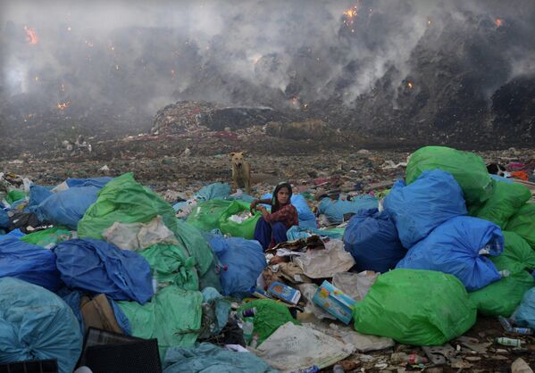 Женщина сортирует предметы после пожара на свалке Бхалсва в Нью-Дели. Свалка занимает площадь более 50 футбольных полей, а ее кучи, порой выше 17-этажного дома - Sputnik Грузия