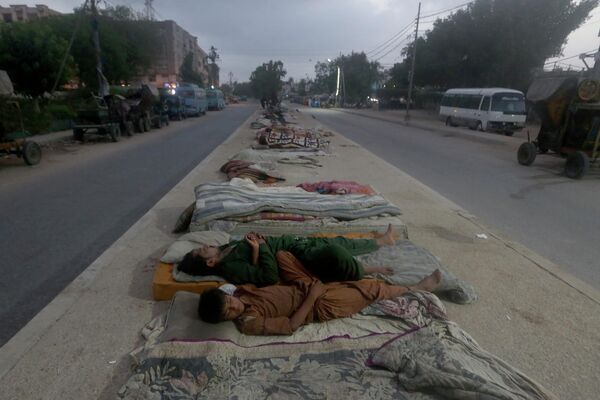 Рабочие спят на середине дороги ранним жарким летним утром в Карачи. В пакистанском портовом городе Карачи и некоторых других частях страны в эти дни продолжалась сильная жара - Sputnik Грузия