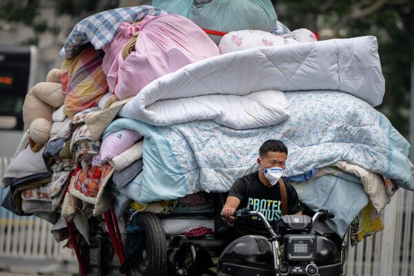 Мужчина в маске везет постельное белье и ткани по улице в Пекине - Sputnik Грузия