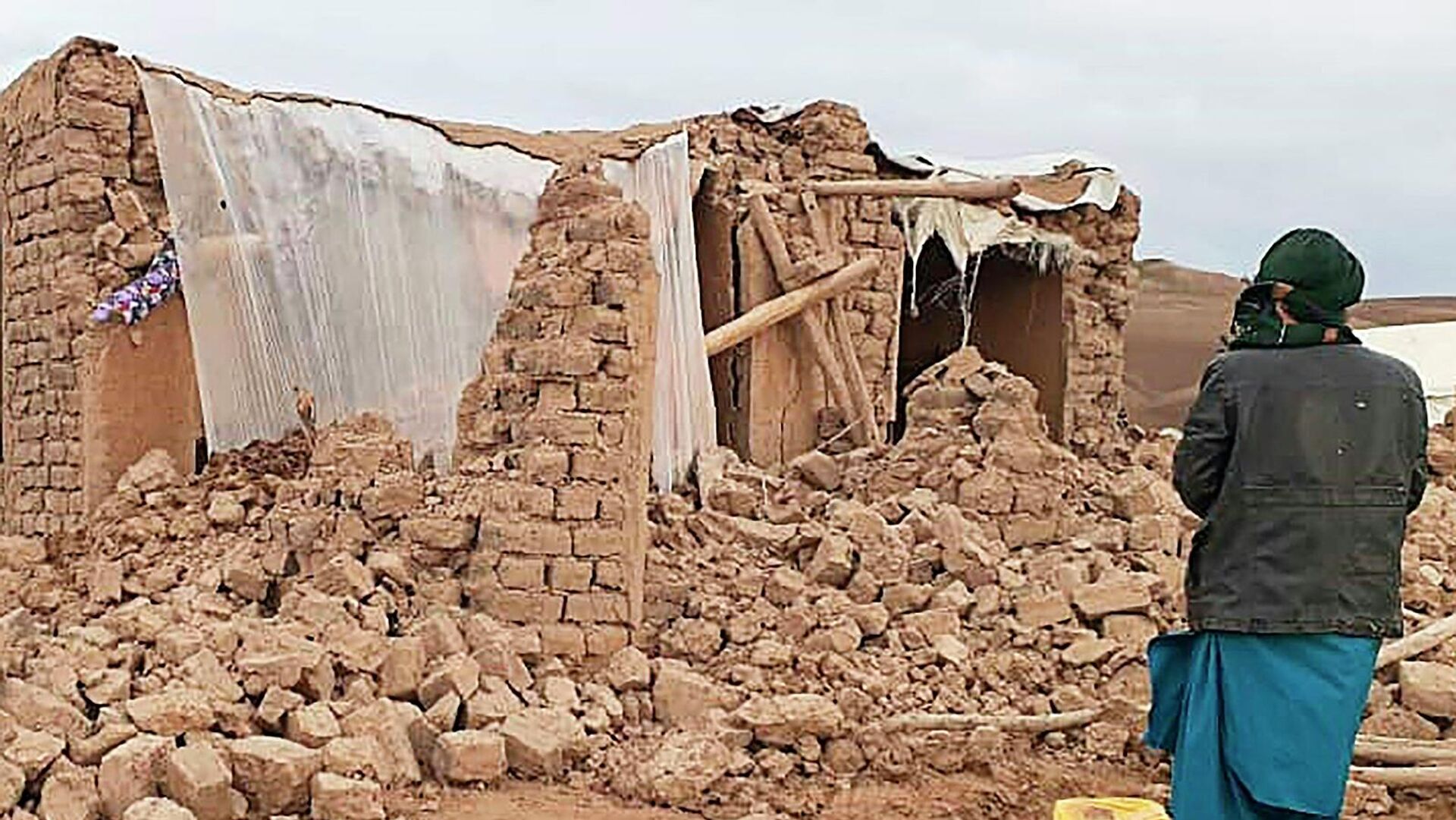 Житель стоит возле разрушенного землетрясением дома в районе Кадис в южной части провинции Бадгис (18 января 2018). Афганистан - Sputnik Грузия, 1920, 22.06.2022