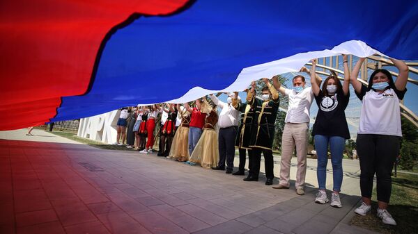 Участники празднований Дня России держат российский флаг в парке Дружбы города Георгиевска Ставропольского края - Sputnik Грузия