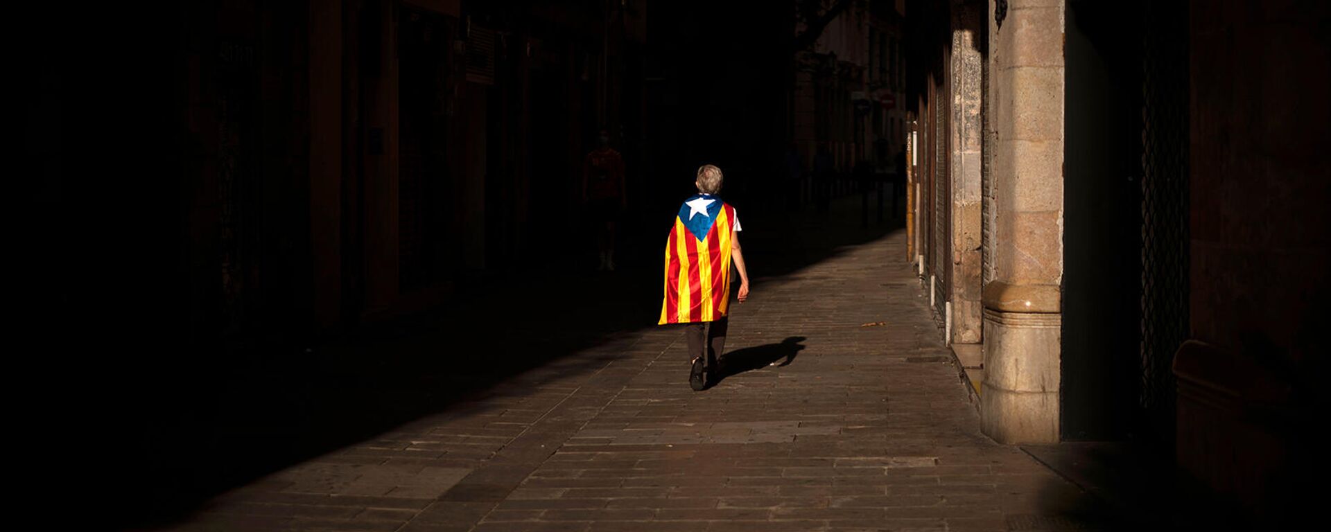 Женщина с флагом эстелады или независимости идет по пустой улице во время Национального дня Каталонии (11 сентября 2020). Барселона - Sputnik Грузия, 1920, 16.07.2022