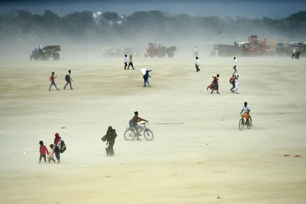 Люди идут среди песчаной бури в Сангаме, месте слияния рек Ганга, Ямуны и мифической Сарасвати, летним днем в Аллахабаде. - Sputnik Грузия