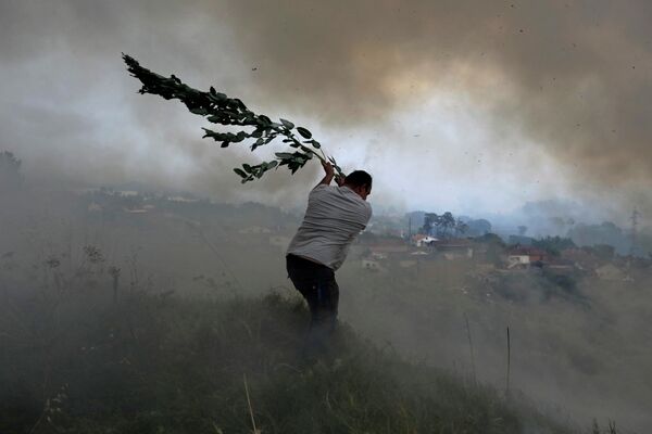 Тысячи человек вынуждены покинуть свои дома. На фото - один из добровольцев так пытается сдержать распространение огня, центральная Португалия - Sputnik Грузия