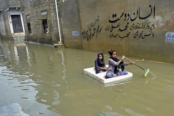 Девочки переплывают на временном плоту затопленную улицу в жилом районе Карачи. В Карачи объявлено чрезвычайное положение из-за продолжительных муссонных дождей - Sputnik Грузия