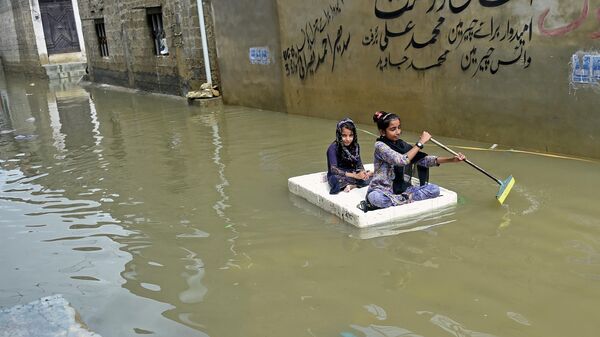Девочки перебираются на плоту через затопленную после сильных дождей улицу в жилом районе Карачи, Пакистан - Sputnik Грузия