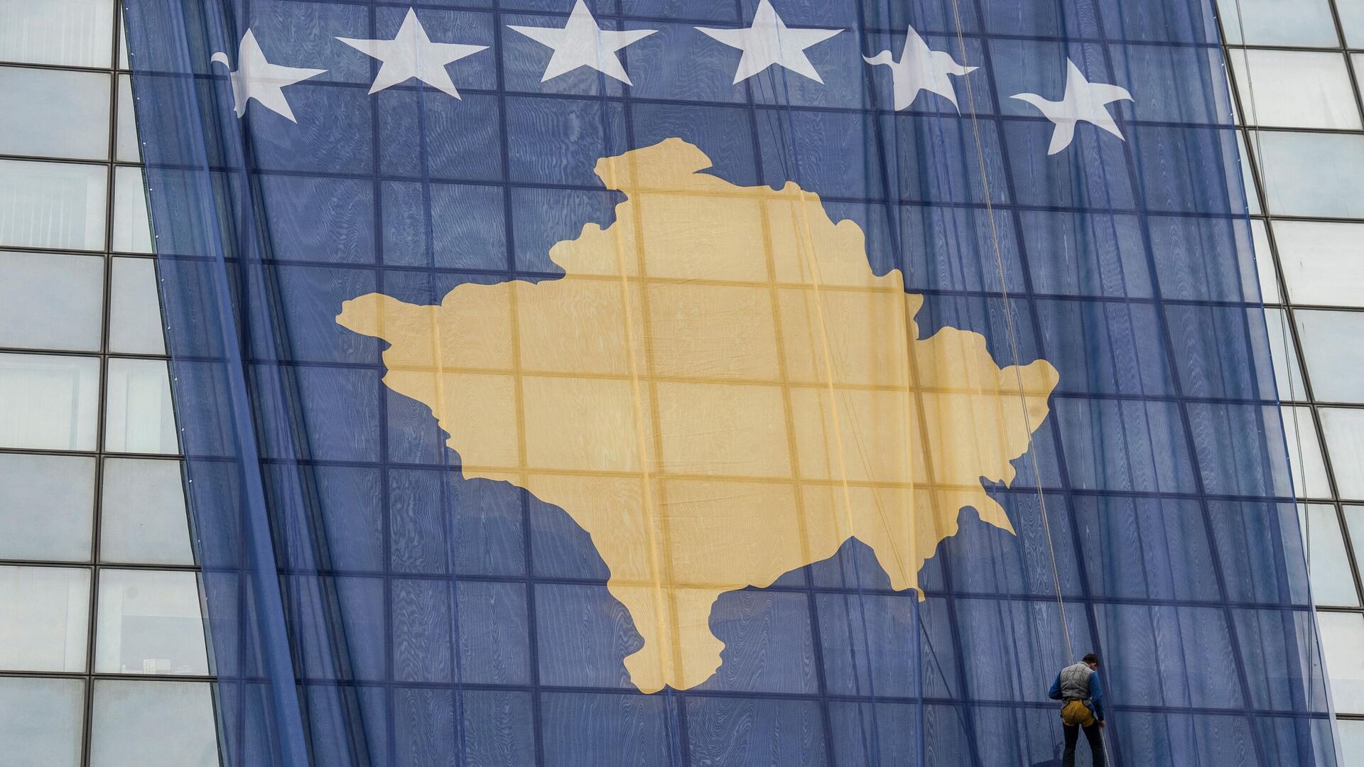 Сотрудник устанавливает гигантский флаг Косово на правительственном здании в Приштине 14 февраля 2018 года в преддверии десятой годовщины независимости Косово. - Sputnik Грузия, 1920, 02.08.2022
