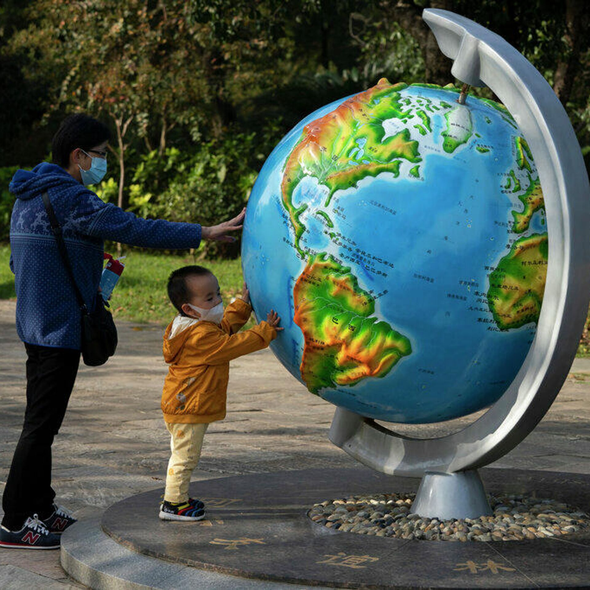 Людей в мире растет а. Мир на планете. Глобус картинка. Человек с глобусом. Дети на глобусе памятник.