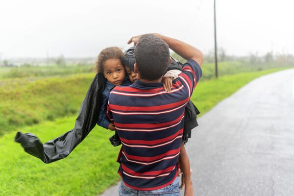 Мужчина несет двоих детей под дождем в поисках убежища после того, как ураган &quot;Иан&quot; затопил их дом в Пинар-дель-Рио - Sputnik Грузия