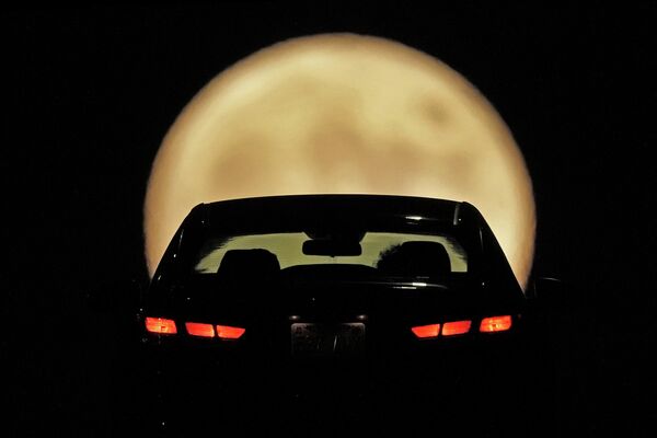 Силуэт автомобилиста вырисовывается на фоне восходящей полной Луны в Шони, штат Канзас - Sputnik Грузия