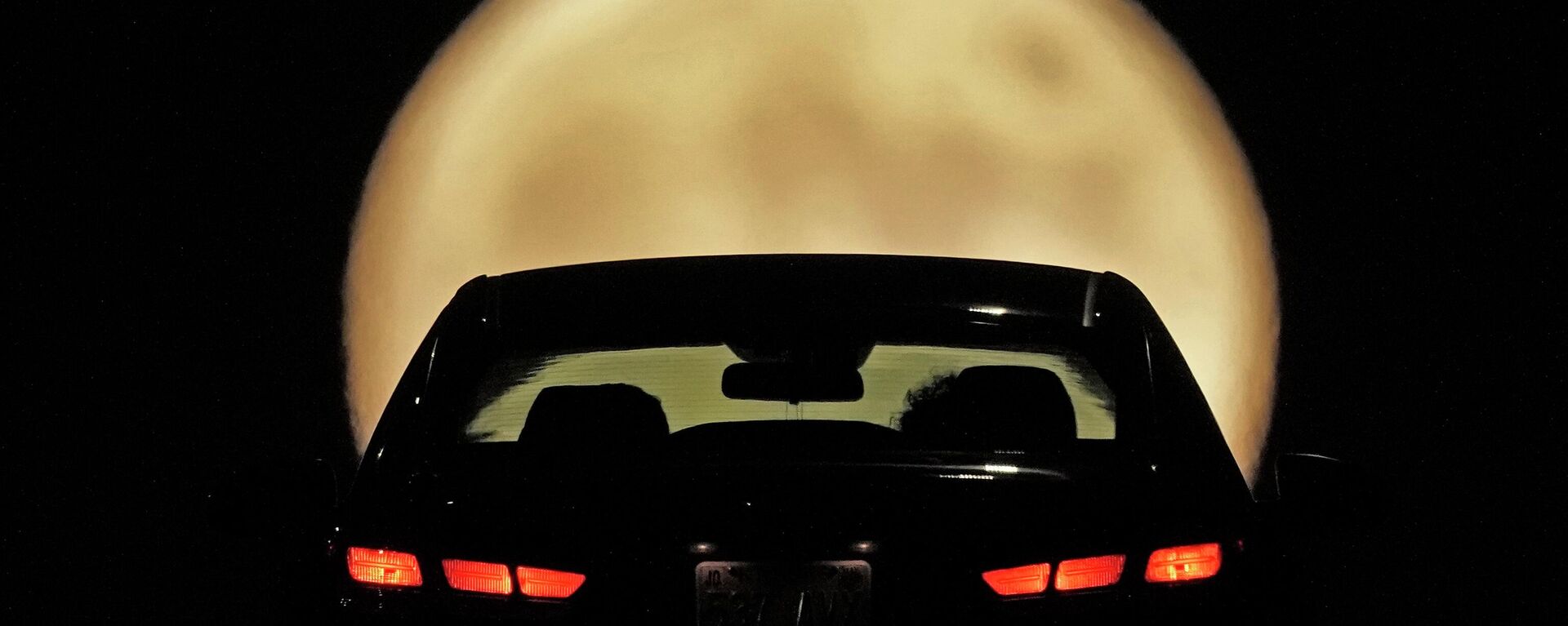 Силуэт автомобилиста вырисовывается на фоне восходящей полной Луны в Шони, штат Канзас - Sputnik Грузия, 1920, 26.05.2023