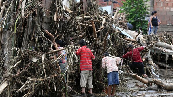 Жители ищут своих пропавших родственников в развалинах дома, разрушенного оползнем во время проливных дождей в Лас-Техериасе, штат Арагуа, Венесуэла - Sputnik Грузия