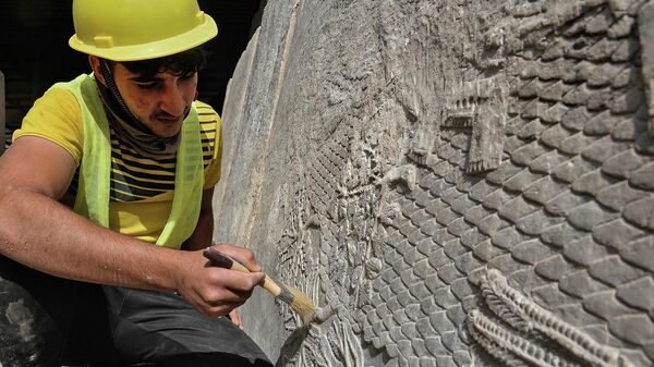 Рабочий занимается очисткой мраморных рисунков, возрастом около 2700 лет, найденных в Мосуле, Ирак - Sputnik Грузия