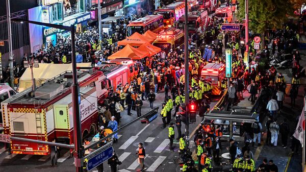 Сеульские спасатели помогают пострадавшим и вывозят погибших с улицы, где во время празднования Хэллоуина из-за давки остановилось сердце у десятков людей, Южная Корея - Sputnik Грузия