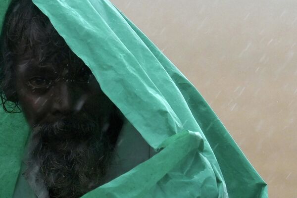 Мужчина под полиэтиленовой пленкой во время сильного муссонного дождя в Индии - Sputnik Грузия