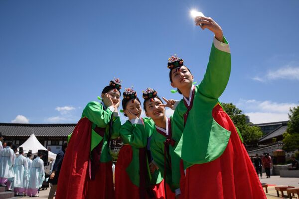 Молодые женщины в традиционных платьях ханбок после церемонии по случаю Дня совершеннолетия в деревне Намсан Ханок в Сеуле - Sputnik Грузия