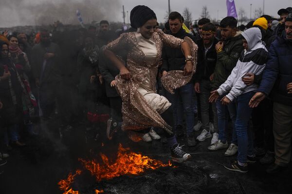 Женщина прыгает через костер во время празднования Навруза в Стамбуле - Sputnik Грузия