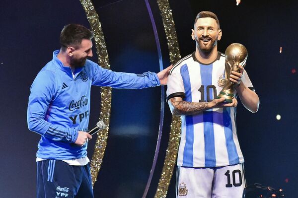 Нападающий сборной Аргентины Лионель Месси рядом со своей статуей во время чествования членов сборной Аргентины за победу на чемпионате мира 2022  - Sputnik Грузия