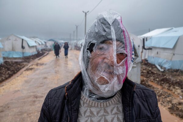 Турецкий мужчина с полиэтиленовым пакетом на голове прячется от дождя в Адыямане, Турция - Sputnik Грузия