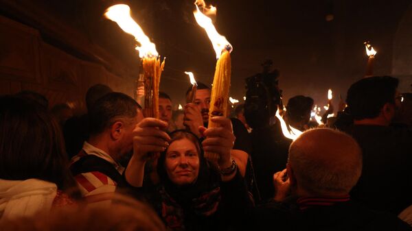 Православные христиане с зажженными свечами во время церемонии благодатного огня в храме Гроба Господня в Старом городе Иерусалима - Sputnik Грузия