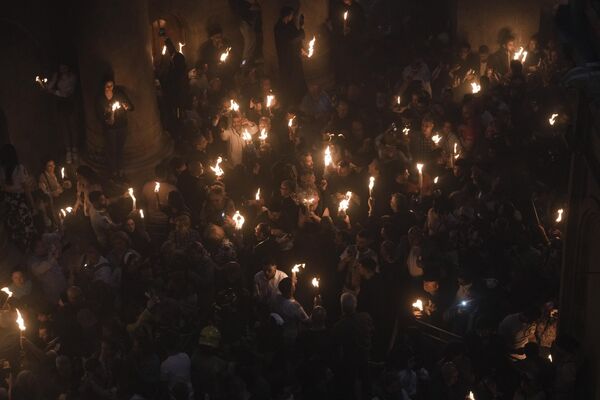 Христианские паломники держат свечи во время церемонии благодатного огня за день до Пасхи в храме Гроба Господня. - Sputnik Грузия