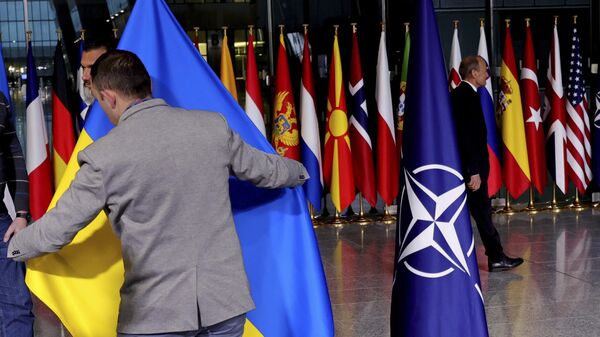 Сотрудник службы протокола поправляет украинский флаг в штаб-квартире НАТО в Брюсселе 7 апреля 2022 года.  - Sputnik Грузия