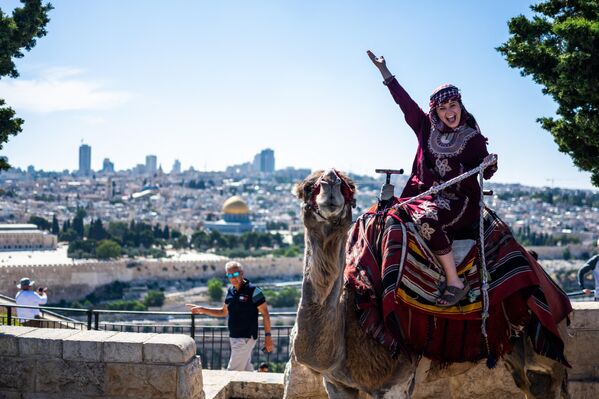 Туристка позирует на верблюде на Масличной горе в Иерусалиме. - Sputnik Грузия