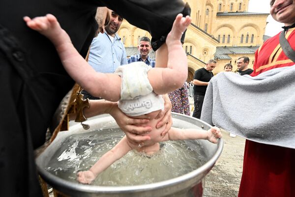 Грузинский православный священник крестит ребенка в Свято-Троицком соборе в Тбилиси. - Sputnik Грузия