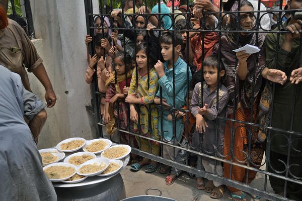 Женщины и дети в очереди за бесплатной едой в пункте раздачи в Пакистане. - Sputnik Грузия