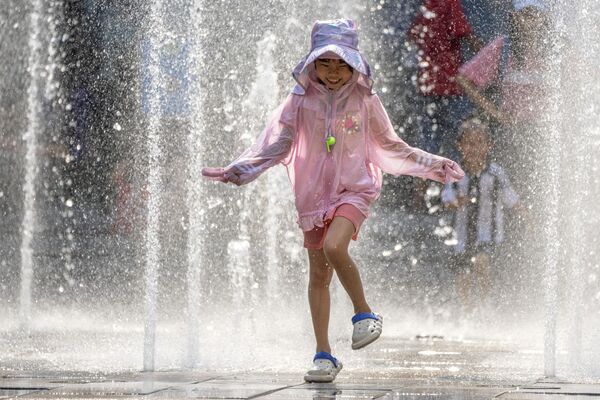 Девочка играет в фонтане во время жаркого дня у торгового центра в Пекине. - Sputnik Грузия