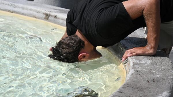 Мужчина опускает голову в воду, чтобы охладиться у фонтана на площади Пьяцца дель Пополо в Риме, Италия - Sputnik Грузия