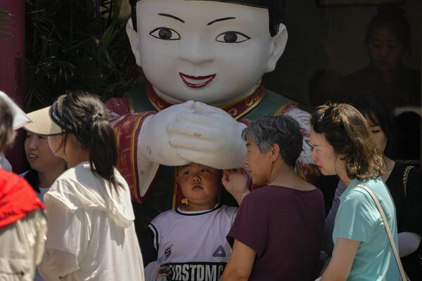 Мальчик прячется у статуе в жаркий день в Пекине. - Sputnik Грузия