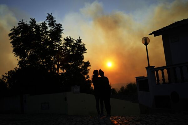 Женщины наблюдают за лесным пожаром возле домов в Алькабидече, недалеко от Лиссабона, Португалия. - Sputnik Грузия