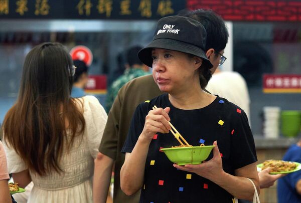 Около 50 тысяч из 86 тысяч случаев COVID-19, выявленных в Китае, были зарегистрированы именно в этом городе. На фото: женщина ест лапшу на одной из улиц Уханя. - Sputnik Грузия