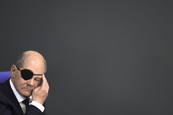 Канцлер Германии Олаф Шольц поправляет черную повязку на глазу во время первого дня дебатов по бюджету на 2024 год в Бундестаге в Берлине. - Sputnik Грузия
