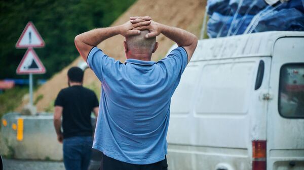 Мужчина смотрит на разрушения на дороге после сильного ливня - Sputnik Грузия