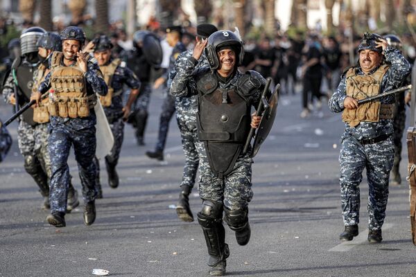 Полицейские по борьбе с беспорядками разгоняют протестующих, собравшихся на площади Тахрир в Багдаде. - Sputnik Грузия