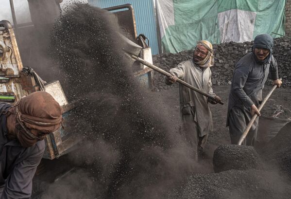 Рабочие сгребают уголь в грузовик на угольном складе на окраине Кабула. - Sputnik Грузия