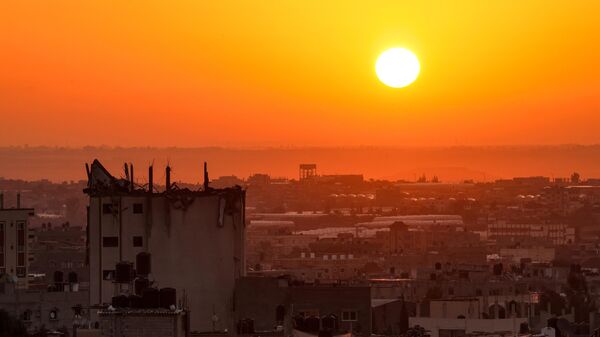 Солнце поднимается из-за поврежденного здания над горизонтом на юге сектора Газа - Sputnik Грузия