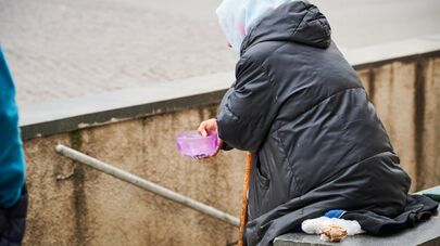 Пожилая женщина, которая просит милостыню