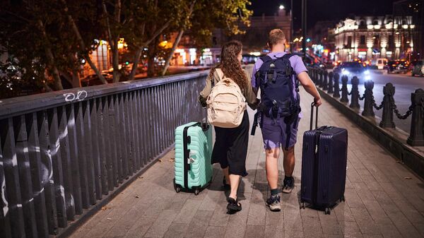 Туристы - парень и девушка с чемоданами идут по столице Грузии - Sputnik Грузия
