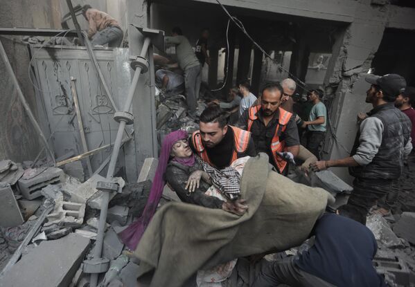 Палестинские спасатели эвакуируют раненую женщину, которая была найдена под обломками разрушенного дома после израильского авиаудара. - Sputnik Грузия
