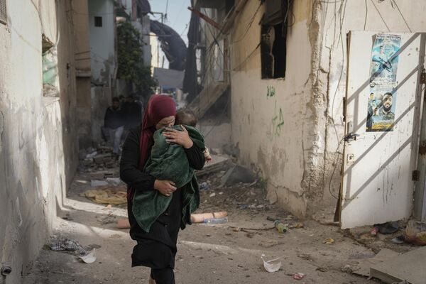 ქალი ბავშვთან ერთად ისრაელის შეტევების შედეგად დაზიანებულ შენობასთან - Sputnik საქართველო