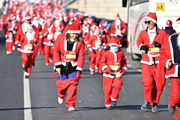 Участница поправляет штаны Санта-Клауса в традиционном рождественском забеге Санта-Клауса в Будапеште. - Sputnik Грузия